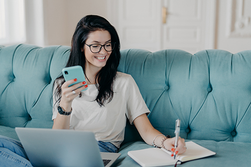 Female copywriter concentrated on remote job, prepares publication, watches webinar to improve skills, reads message, installs new application, uses free internet connection, smiles happily.